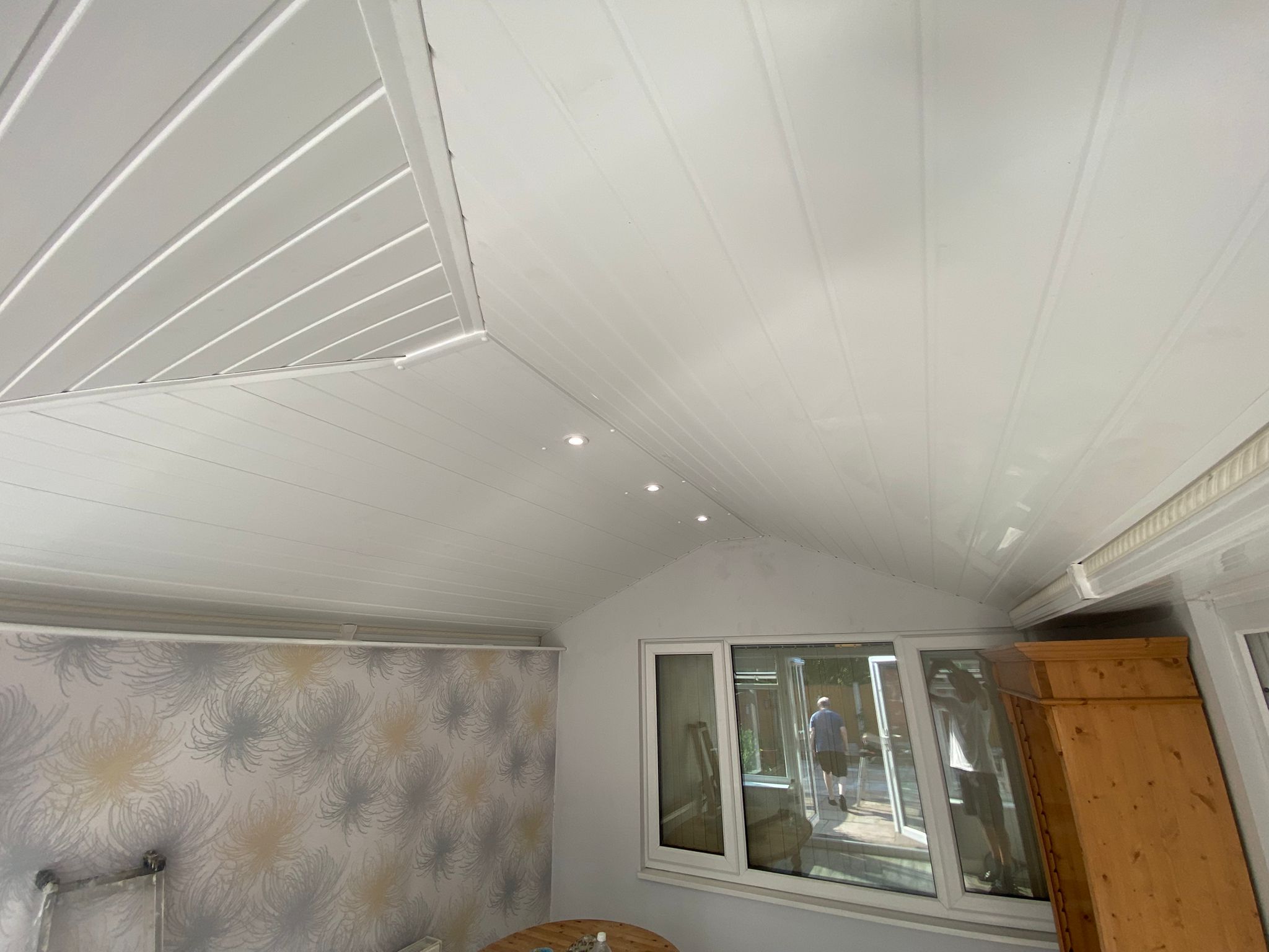 Completed white-cladded conservatory ceiling with recessed spotlights and fitted blinds